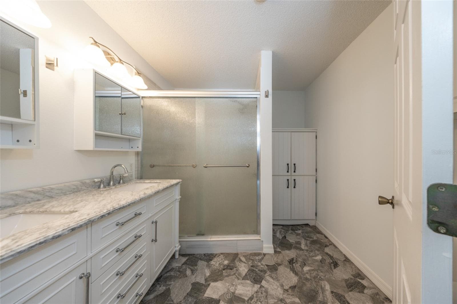 primary bathroom has been updated, including granite countertops, stone floors and large storage cabinet - 11 LANCASTER LN, PALM COAST