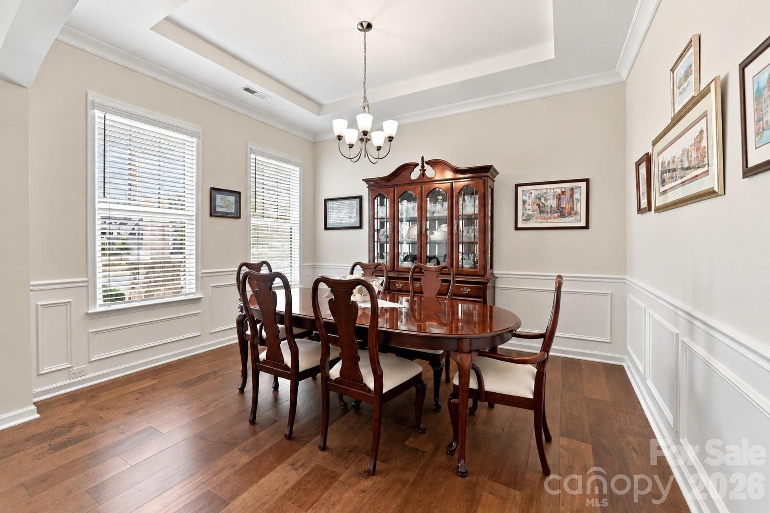 Elegant formal dining room with wide plank hardwood floors, tray ceiling, crown molding and detailed picture-frame wainscoting. Space to bring everyone together for holiday feasts, celebrations and memorable dinners. - 8504 Hope Run Court, Indian Land