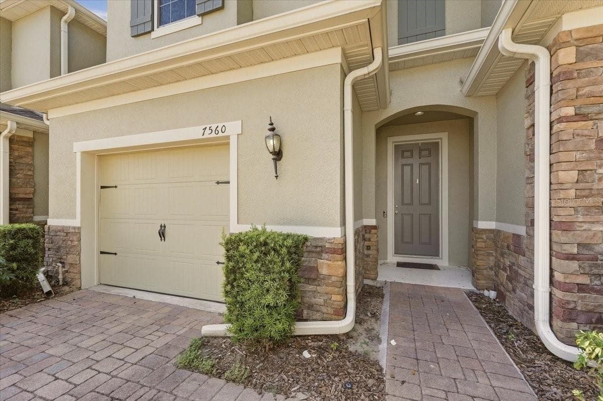 Welcoming entryway with stone detail, covered walkway, and attached one-car garage - 7560 ALOMA PINES CT, WINTER PARK