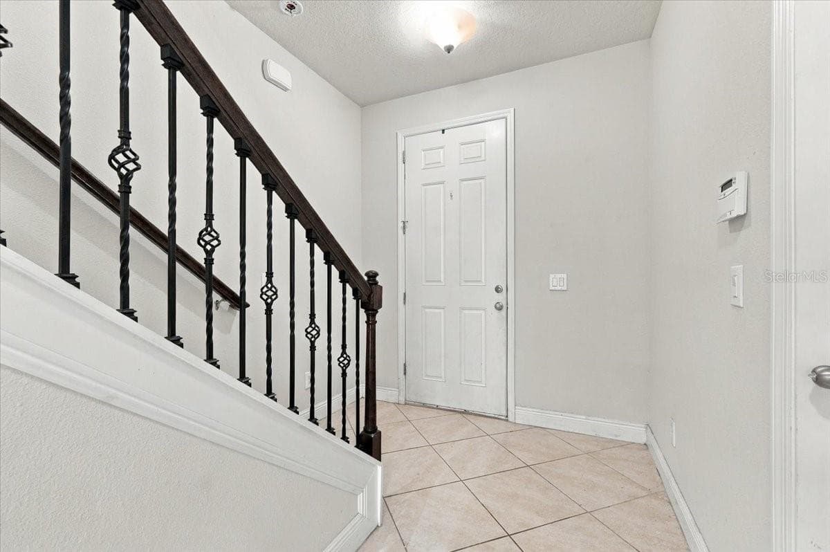 Bright foyer featuring tile flooring and an elegant wrought-iron stair railing - 7560 ALOMA PINES CT, WINTER PARK