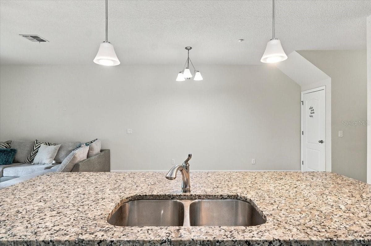 Granite kitchen island with double basin sink and stylish pendant lighting - 7560 ALOMA PINES CT, WINTER PARK