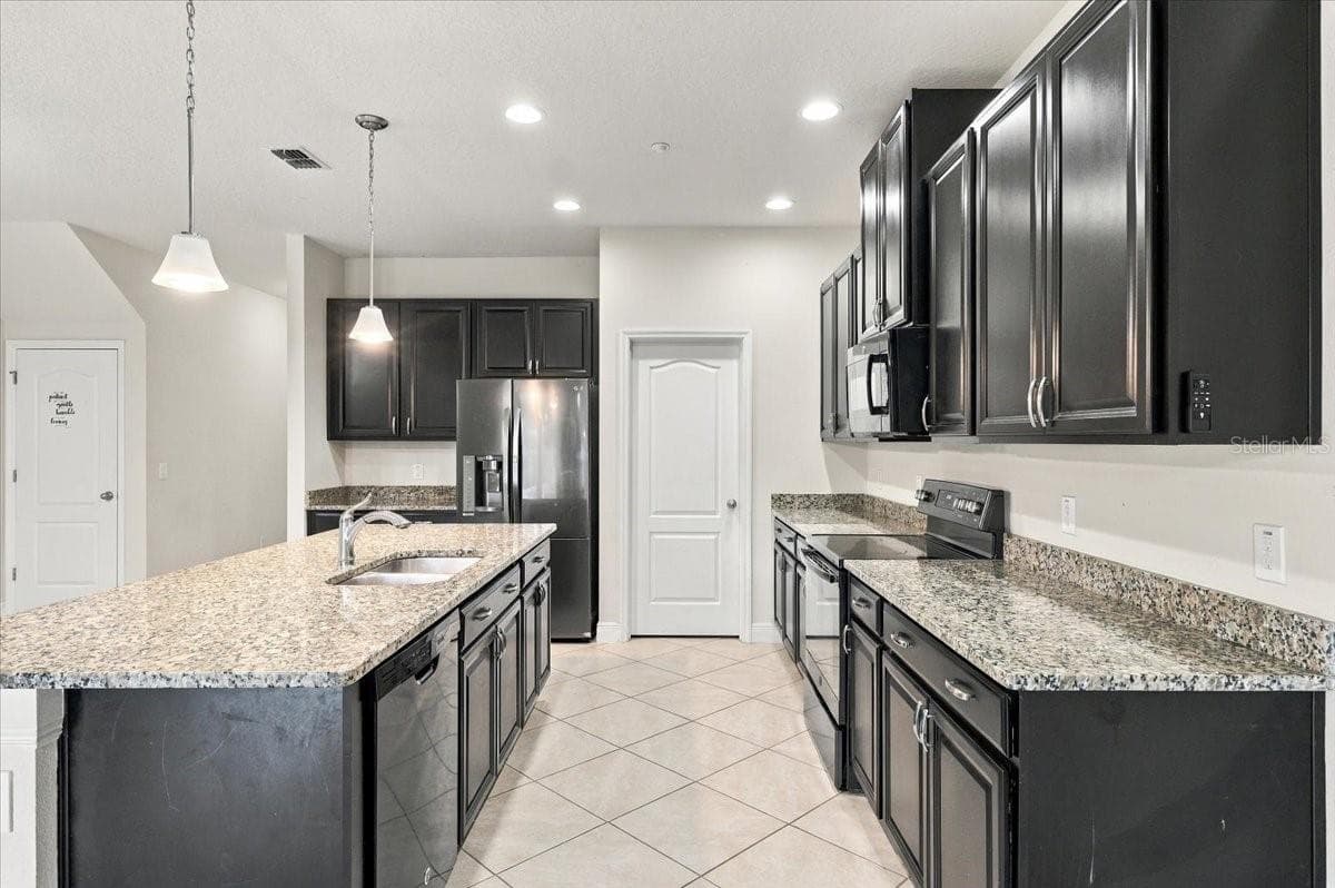 Well-appointed kitchen with rich cabinetry, granite counters, and stainless steel appliances - 7560 ALOMA PINES CT, WINTER PARK