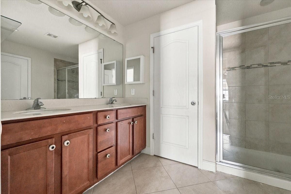 Primary ensuite bath featuring dual-sink vanity and a glass-enclosed walk-in shower - 7560 ALOMA PINES CT, WINTER PARK