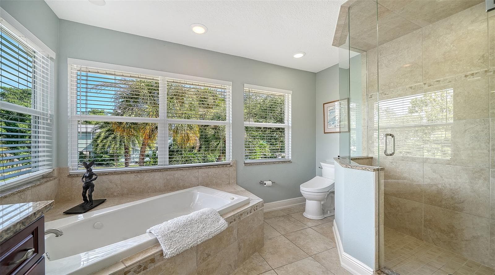 Spacious primary bath with jetted tub, separate shower and abundant natural light. - 5188 SIESTA WOODS DR, SARASOTA