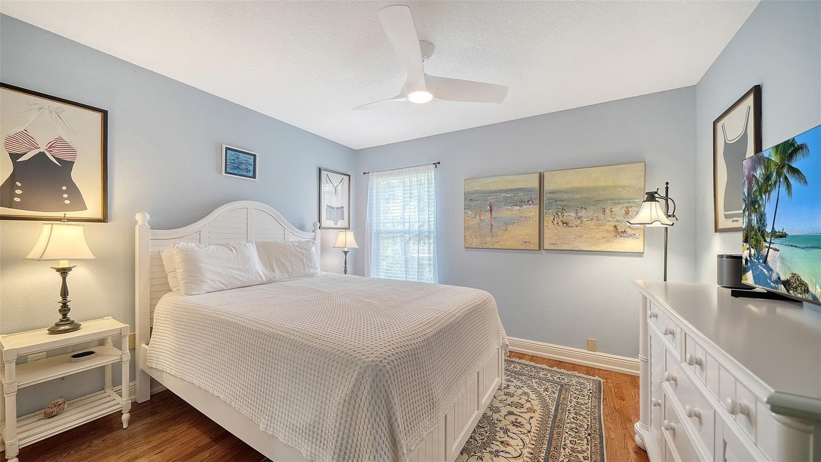 Comfortable guest bedroom with hardwood flooring and natural light. - SARASOTA