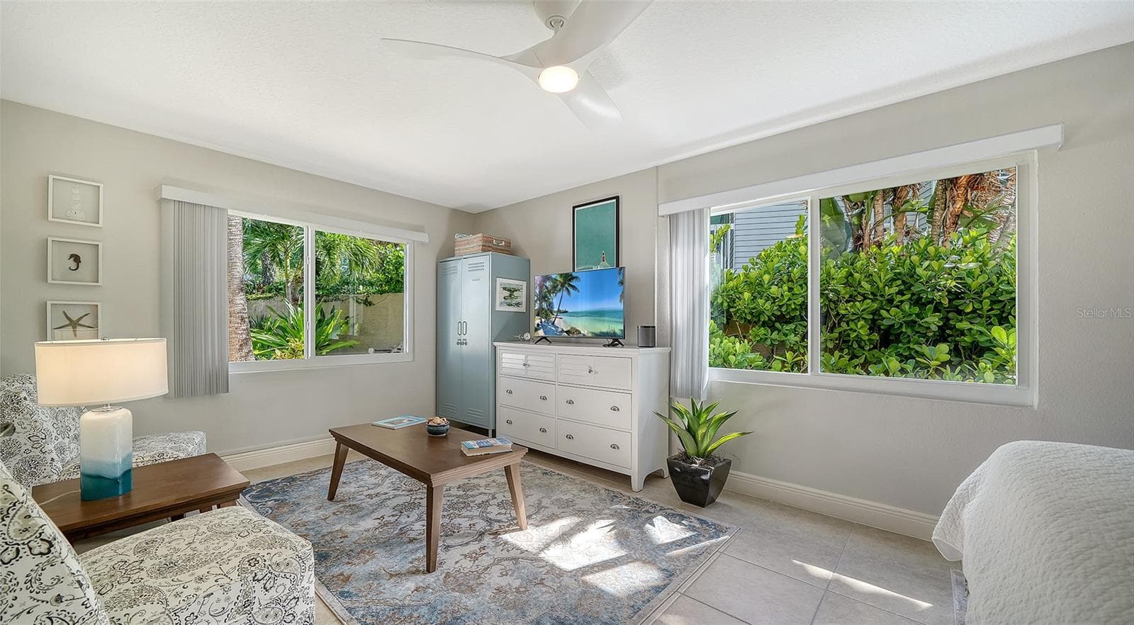 Bright guest bedroom with multiple windows overlooking the lush landscaping. - SARASOTA
