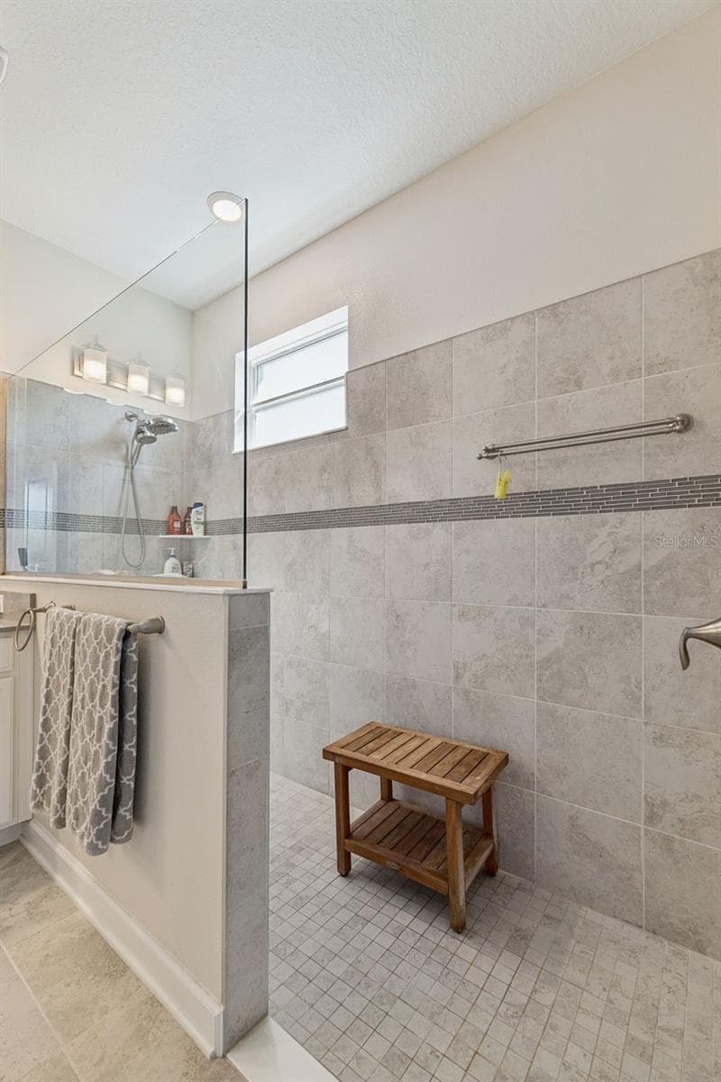 Handicap Accessible Tiled Shower adorned with Decorative Listello Tile and Glass Enclosure - 4075 BEDFORD AVE, WINTER HAVEN