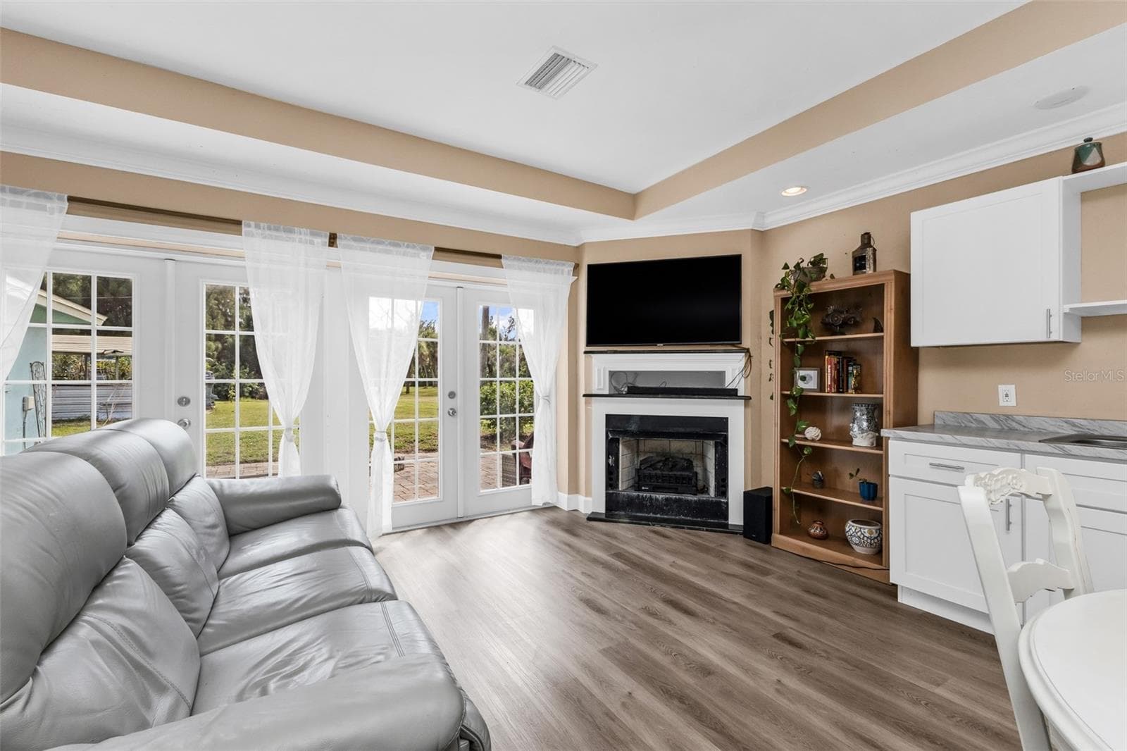 Open living room and kitchen with fireplace with French doors leading to paver patio - 3407 ISLAND VIEW DR, PUNTA GORDA