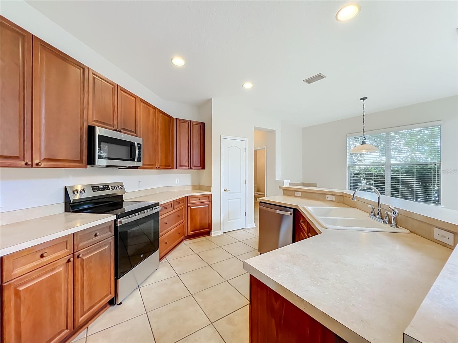 Wood cabinets, new appliances, closet pantry, a long breakfast bar, and ceramic tile floors - 12809 HOLDENBURY LN, WINDERMERE