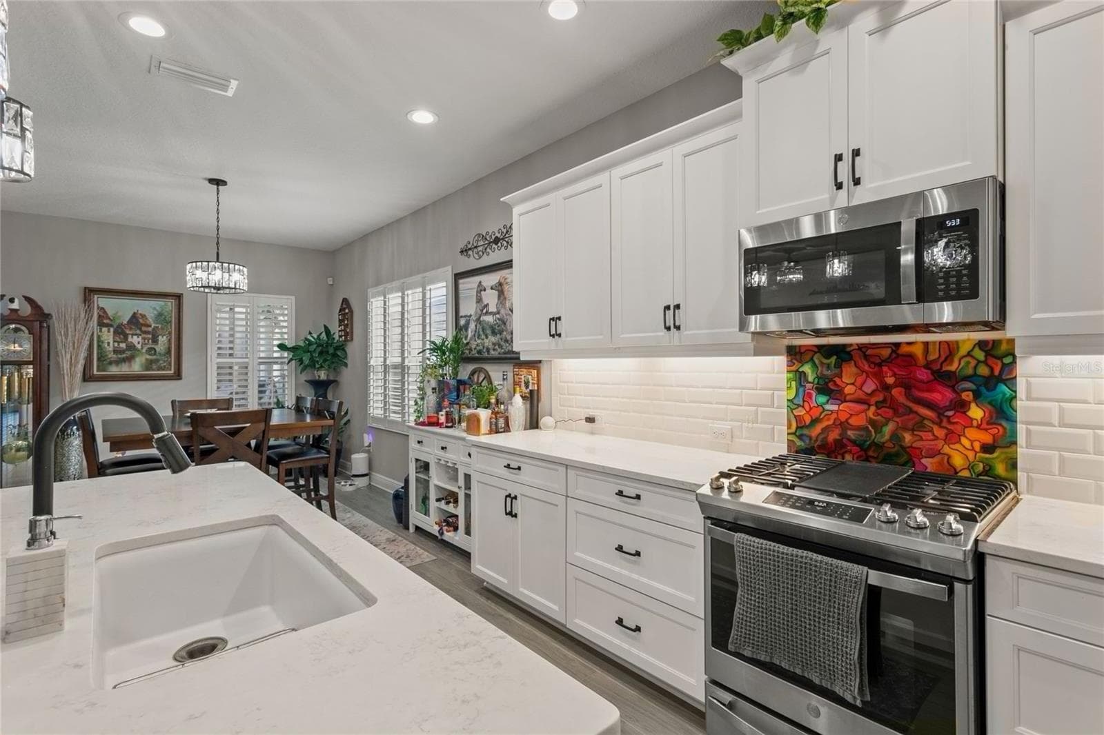 The kitchen continues with white cabinetry, quartz countertops, stainless-steel appliances, and a spacious island with an integrated sink that enhances the open, bright flow into the dining area. - 10625 FALLING LEAF CT, PARRISH