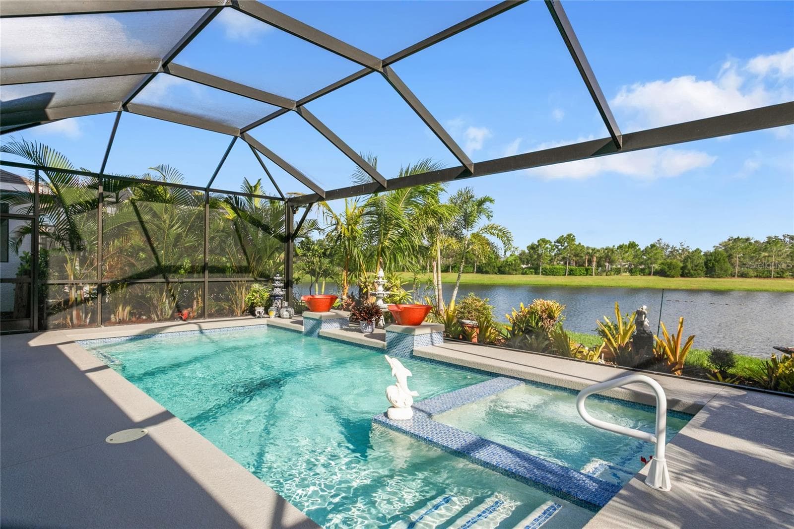 The outdoor living area showcases a panoramic-view screened lanai overlooking the pool and lake, creating an open, unobstructed backdrop that enhances the home’s indoor-outdoor flow and provides a serene, resort-style setting - 10625 FALLING LEAF CT, PARRISH