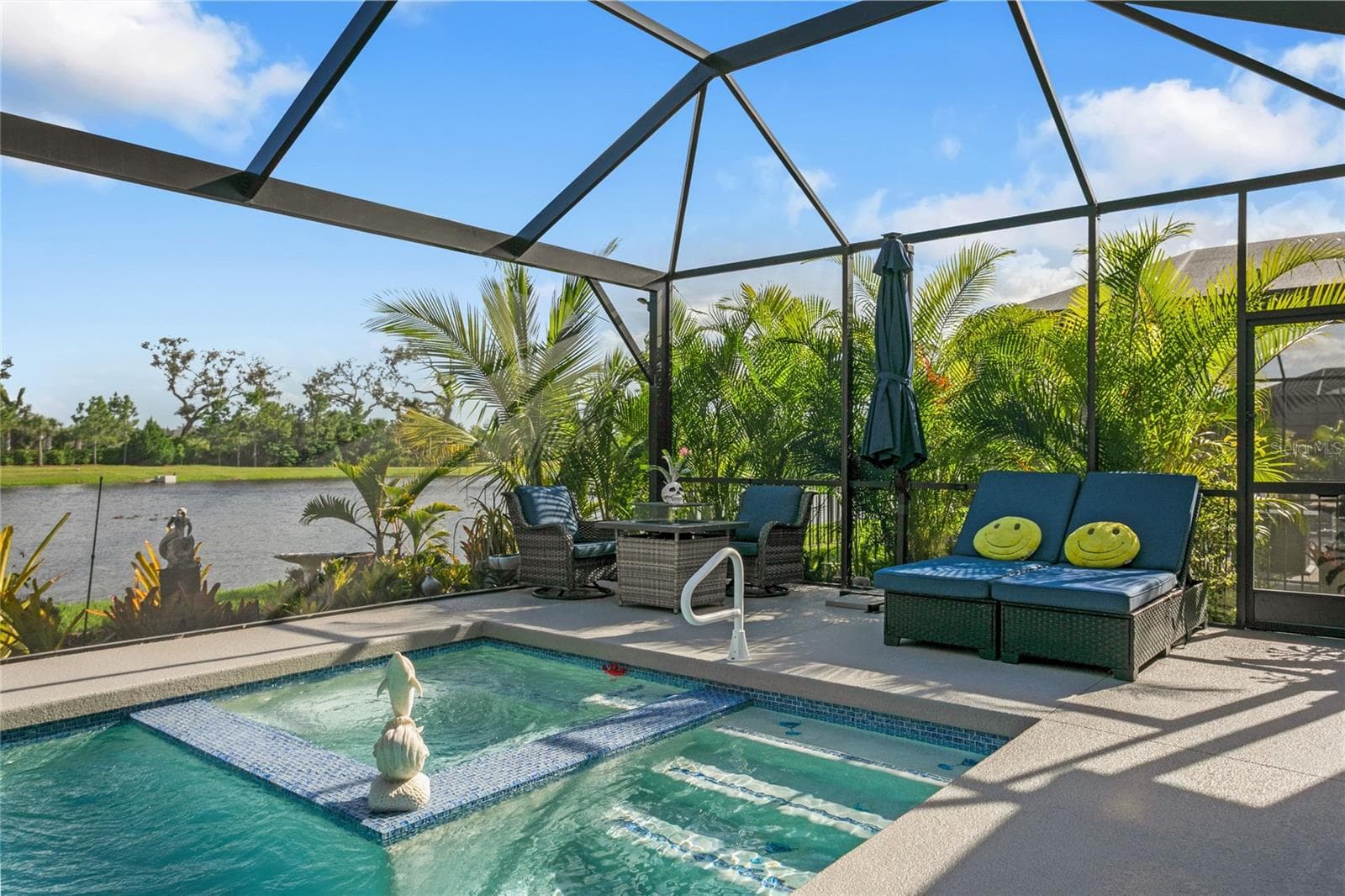 The screened lanai showcases wide, unobstructed views of the lake, creating a serene backdrop that enhances the pool area and elevates the home’s indoor-outdoor living experience. - 10625 FALLING LEAF CT, PARRISH