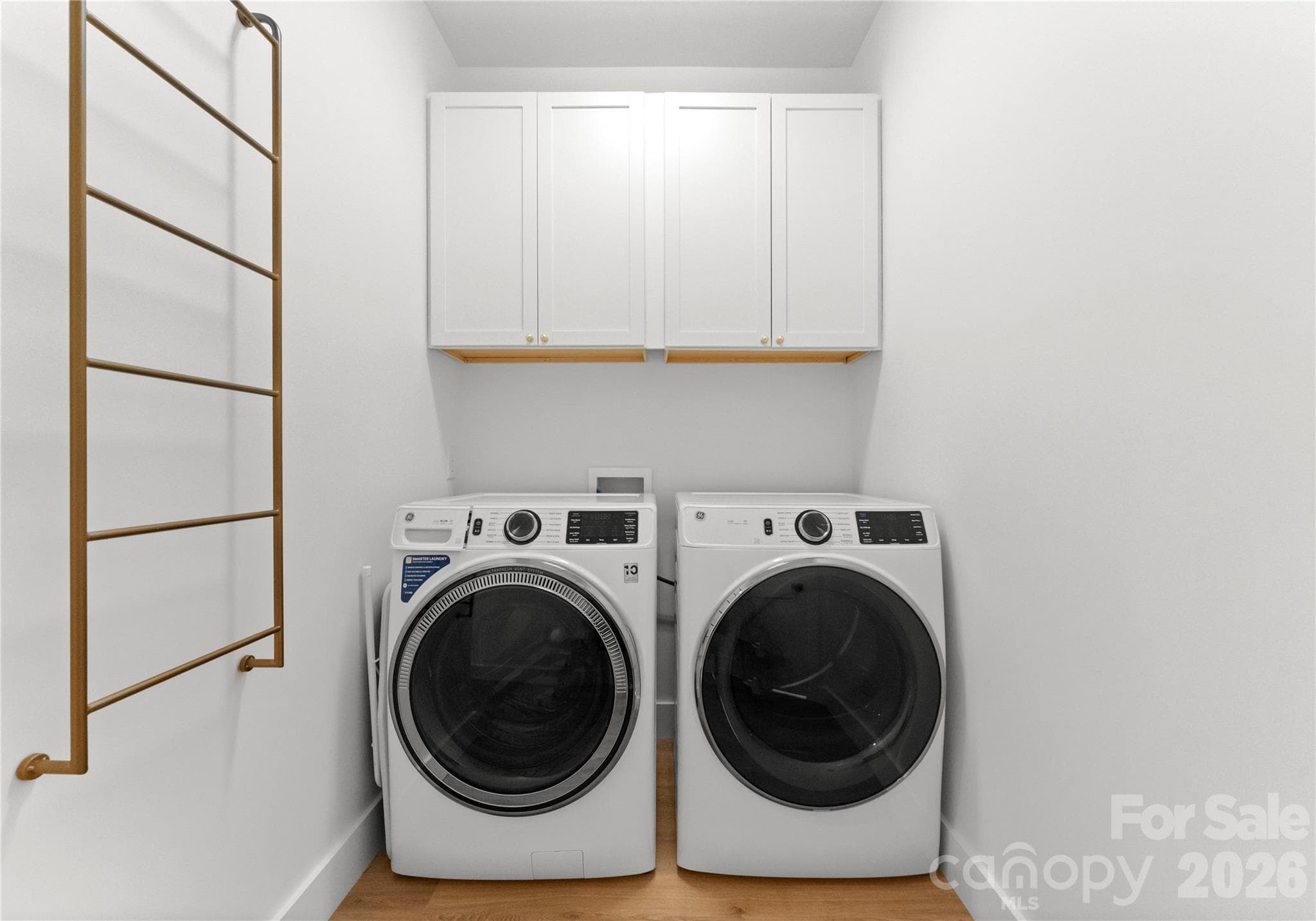 The laundry room pairs a side-by-side washer and dryer with overhead cabinetry for convenient storage. - 143 Hideaway Lane, Mooresville