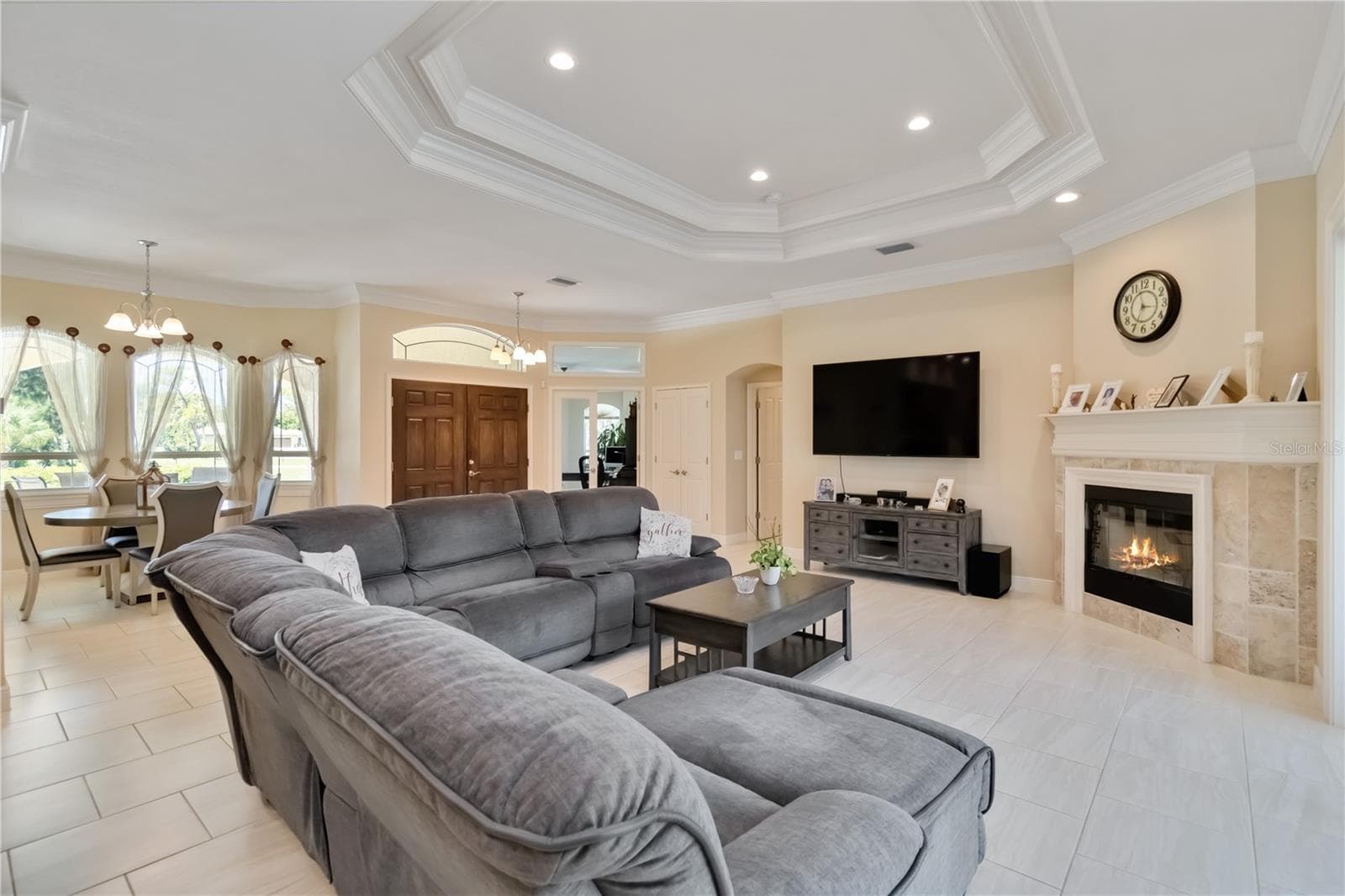 Another view of the open floor plan, tray ceiling, and wood fireplace. The open door th the right of the closet leads to the primary bedroom. This home has a split floorplan. - 1991 HEASLEY, ENGLEWOOD