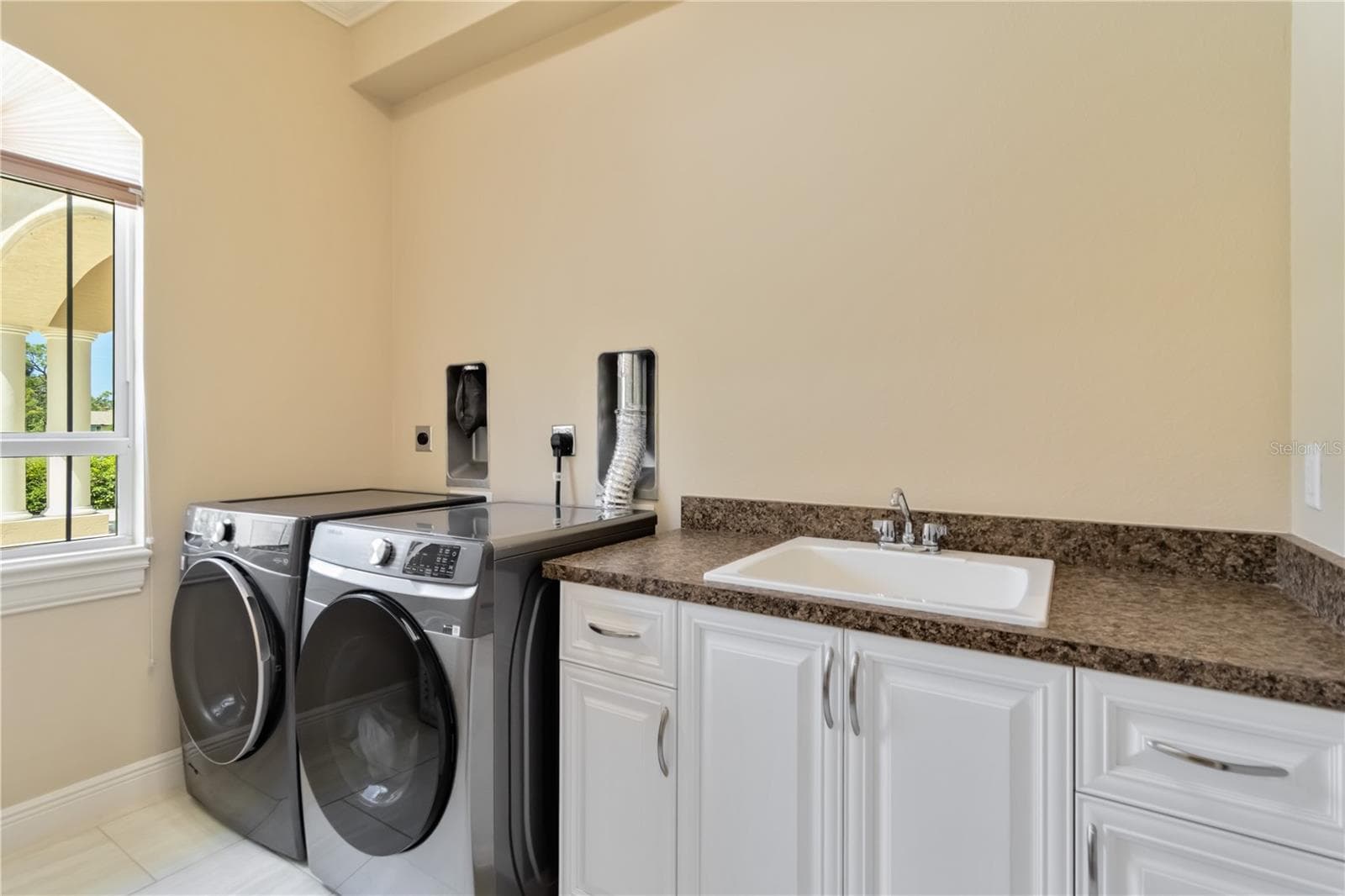 The Landry room offers storage shelving on the wall not shown in this picture.  Notice the two outlets and dryer vents. This laundry room was designed to have two washers and two dryers. They would be the stackable kind as shown in this picture. - 1991 HEASLEY, ENGLEWOOD