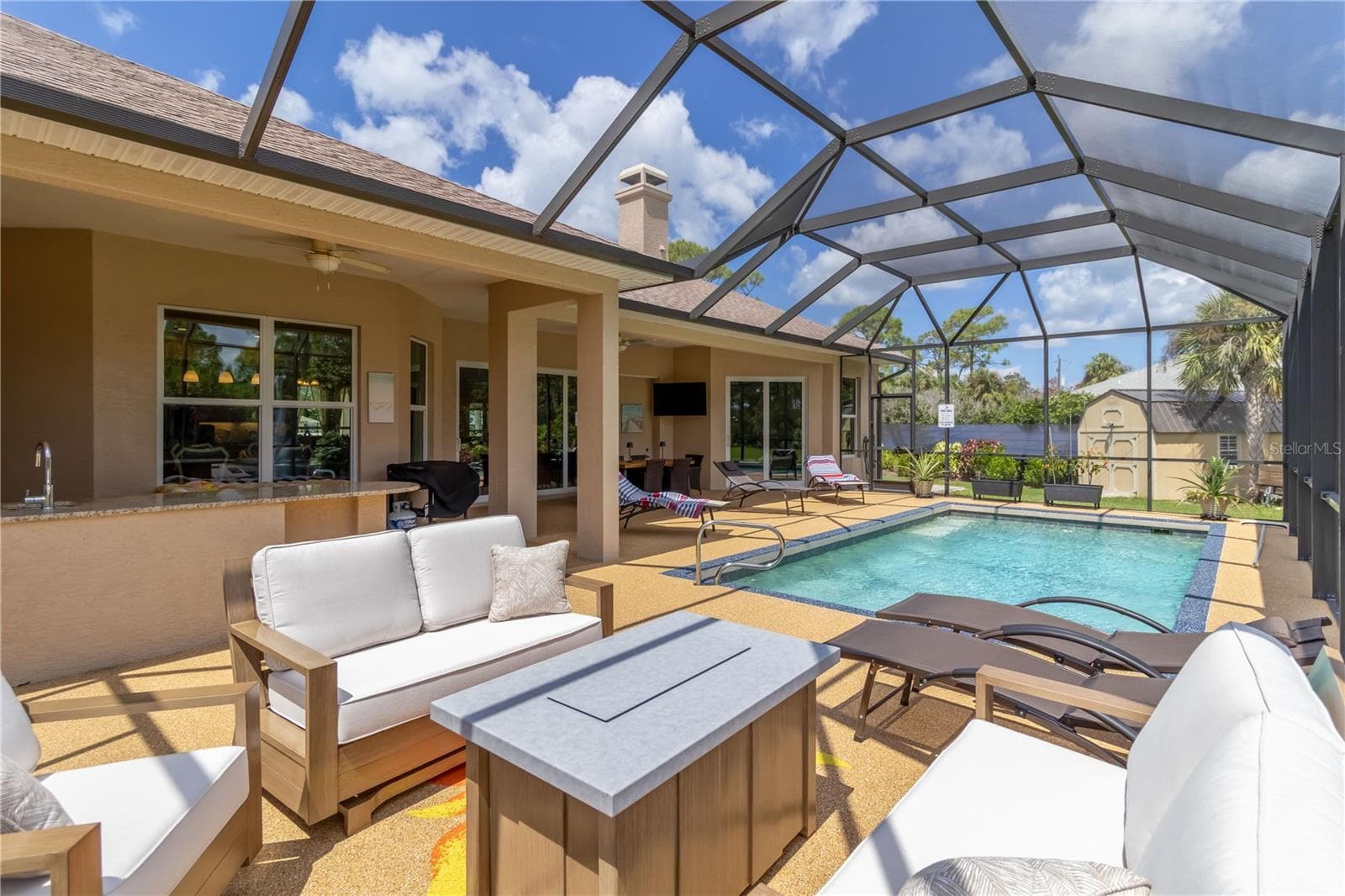 The covered area has two ceiling fans and can lights. Notice the TV (swim and watch your favorite shows at the same time!) and the outdoor kitchen. The curved part of the granite counters is designed for 2-3 bar stools. - 1991 HEASLEY, ENGLEWOOD