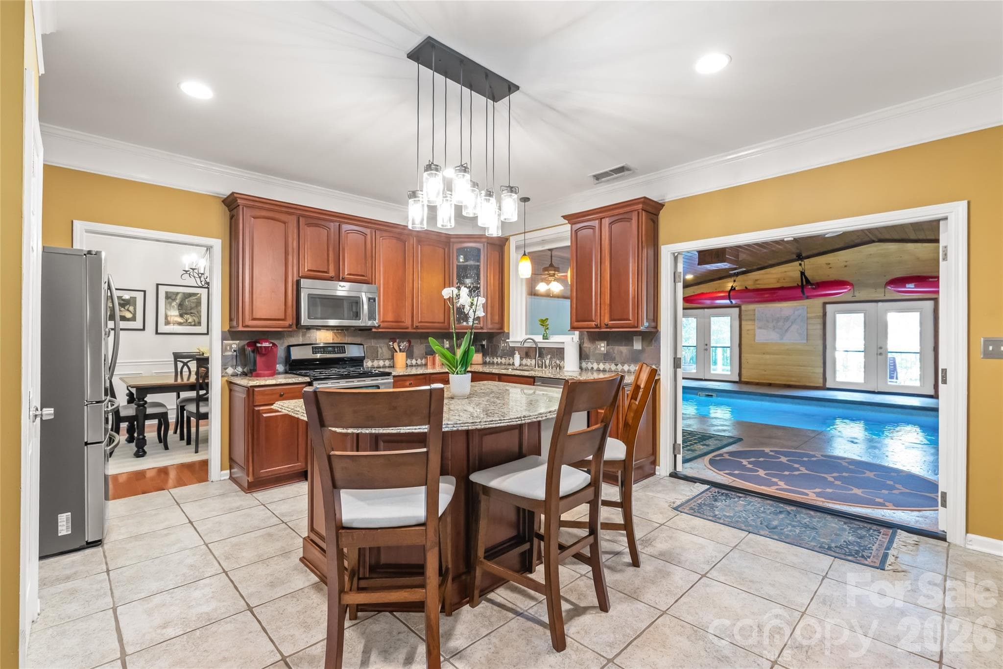 Beautiful cabinetry adds ample storage. Granite with tile backsplash adds style. Double doors lead to the climate controlled pool area - 13934 Kings Carriage Lane, Charlotte
