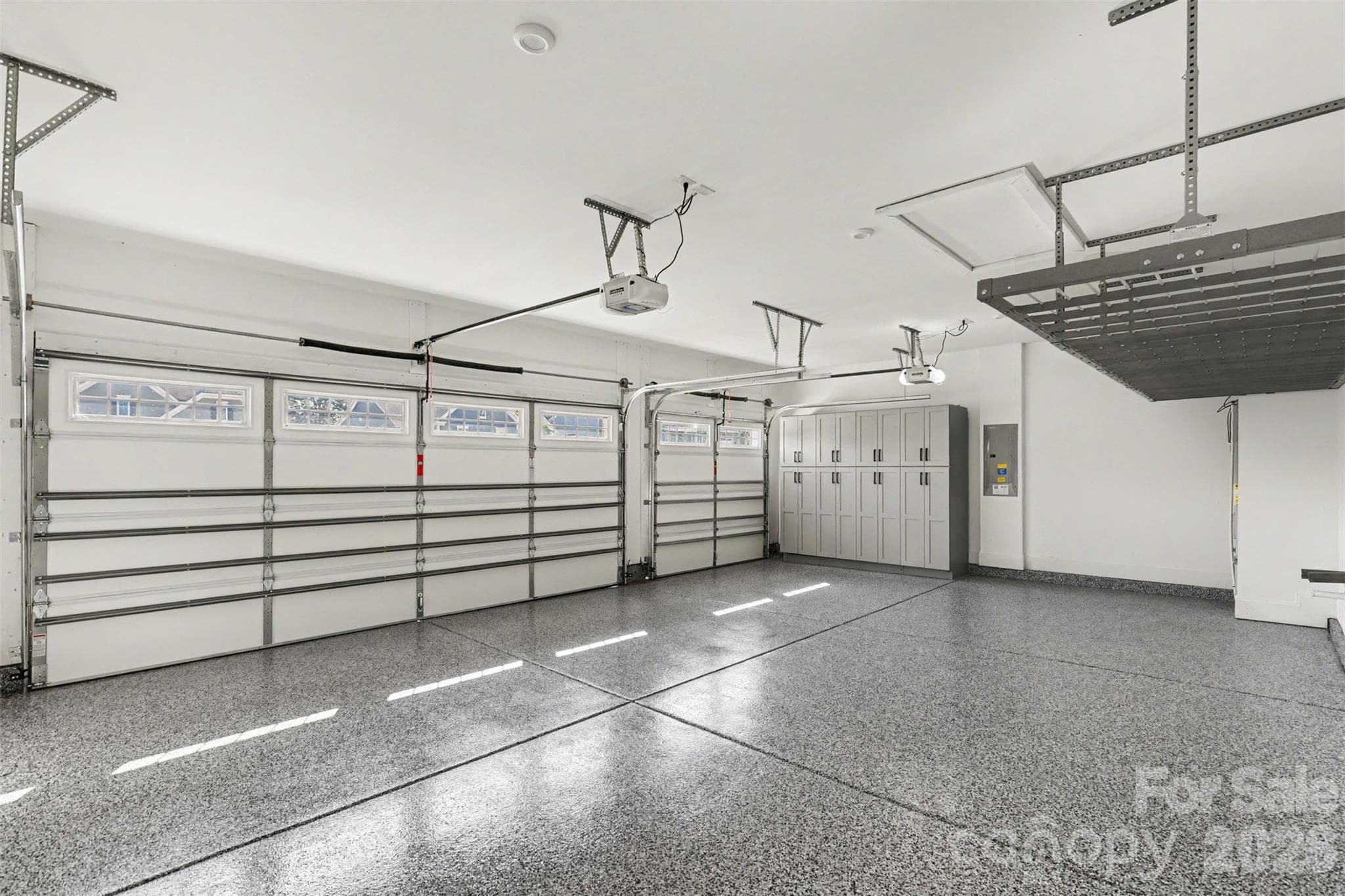 This garage doesn't just park cars. Epoxy floors that shine, a handsome bank of storage cabinets, and an overhead rack for everything you don't want cluttering the floor. Three bays, zero excuses. - 8027 Longwaters Court, York