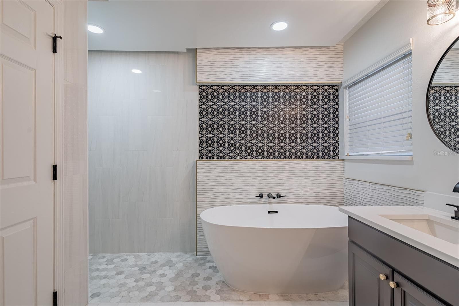 Completely gutted and rebuilt in 2022 with an investment of approximately $32,000, the primary bathroom includes a floating quartz double vanity, illuminated mirrors, an oversized walk in rain shower, multiple shower fixtures and lighted niches. - 14585 CHEEVER ST, ORLANDO