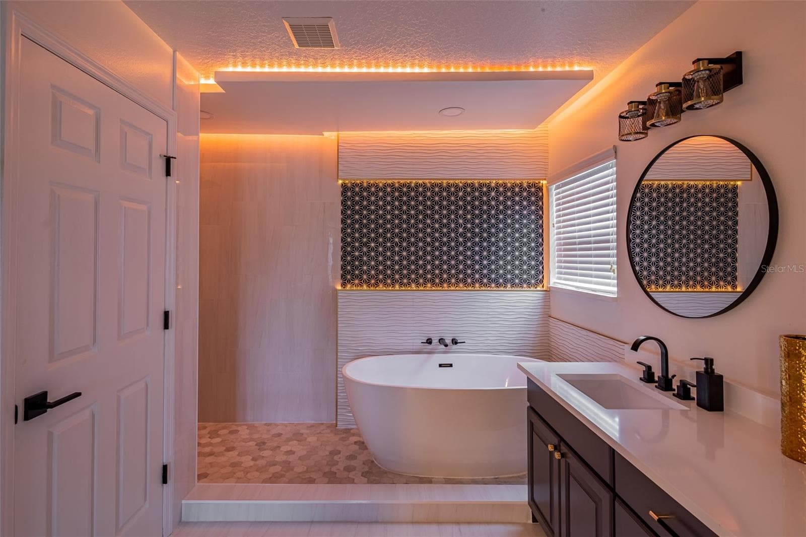Completely gutted and rebuilt in 2022 with an investment of approximately $32,000, the primary bathroom includes a floating quartz double vanity, illuminated mirrors, an oversized walk in rain shower, multiple shower fixtures and lighted niches. - 14585 CHEEVER ST, ORLANDO