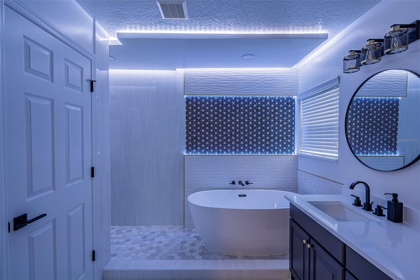 Completely gutted and rebuilt in 2022 with an investment of approximately $32,000, the primary bathroom includes a floating quartz double vanity, illuminated mirrors, an oversized walk in rain shower, multiple shower fixtures and lighted niches. - 14585 CHEEVER ST, ORLANDO