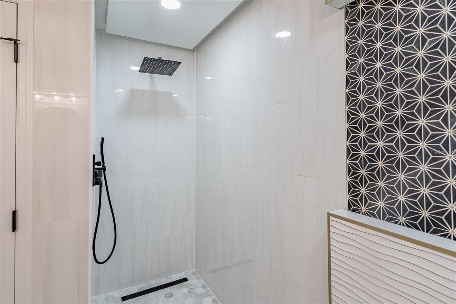 Completely gutted and rebuilt in 2022 with an investment of approximately $32,000, the primary bathroom includes a floating quartz double vanity, illuminated mirrors, an oversized walk in rain shower, multiple shower fixtures and lighted niches. - 14585 CHEEVER ST, ORLANDO