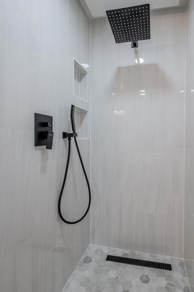 Completely gutted and rebuilt in 2022 with an investment of approximately $32,000, the primary bathroom includes a floating quartz double vanity, illuminated mirrors, an oversized walk in rain shower, multiple shower fixtures and lighted niches. - 14585 CHEEVER ST, ORLANDO