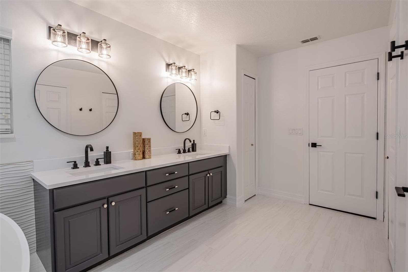 Completely gutted and rebuilt in 2022 with an investment of approximately $32,000, the primary bathroom includes a floating quartz double vanity, illuminated mirrors, an oversized walk in rain shower, multiple shower fixtures and lighted niches. - 14585 CHEEVER ST, ORLANDO