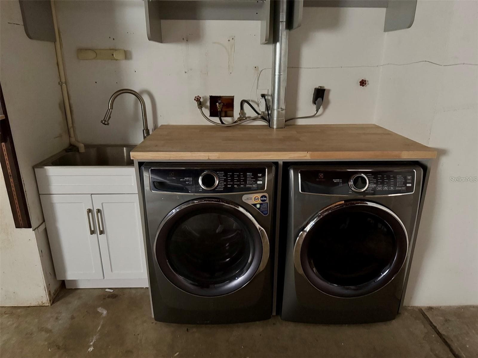 Laundry facilities are located in the garage with a sink and storage. - 2260 SAINT CHARLES DR, CLEARWATER