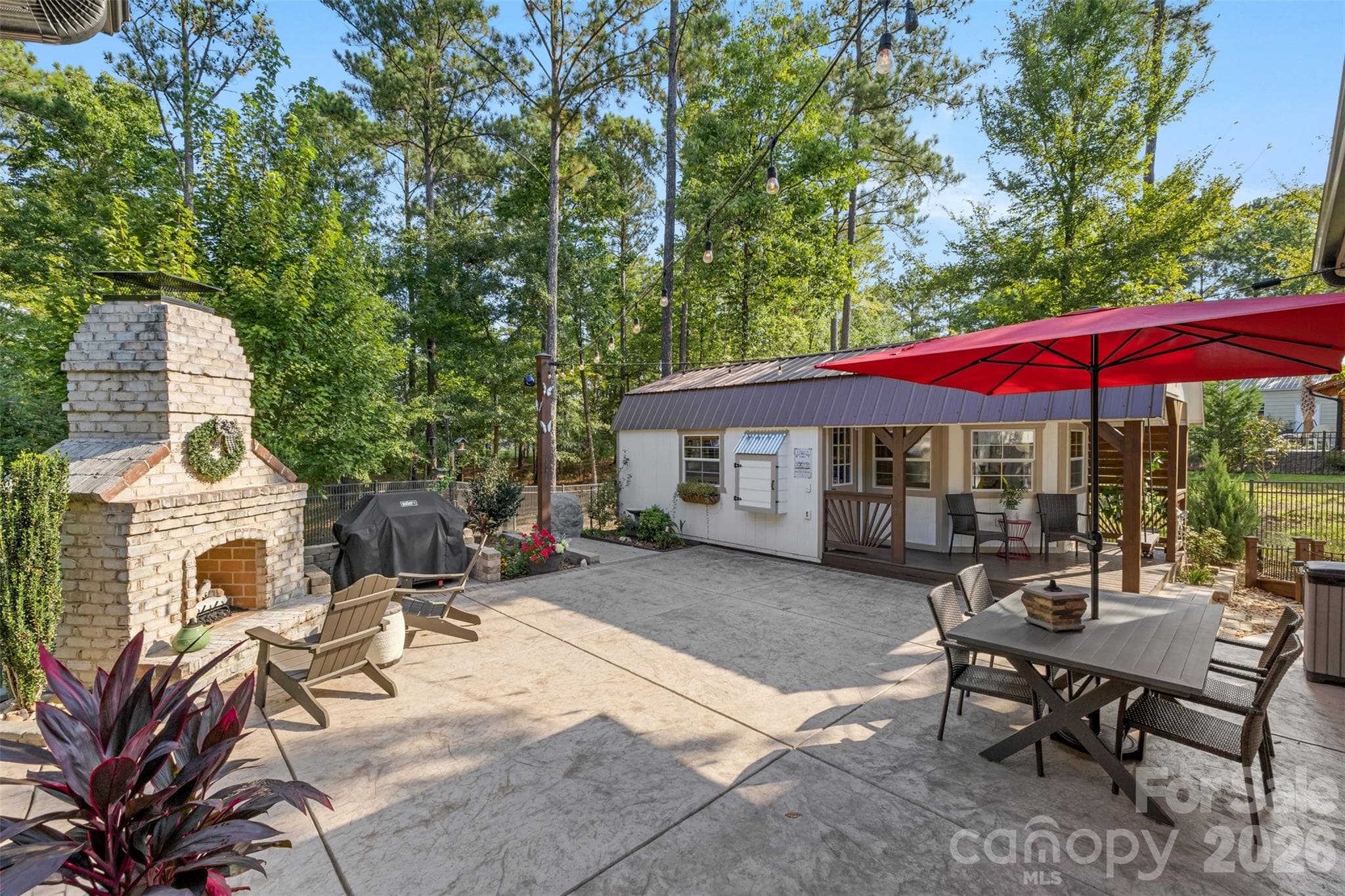 Spacious patio with an outdoor fireplace, dining area, and string lights for entertaining - 1604 Aragon Beach Road, Rock Hill
