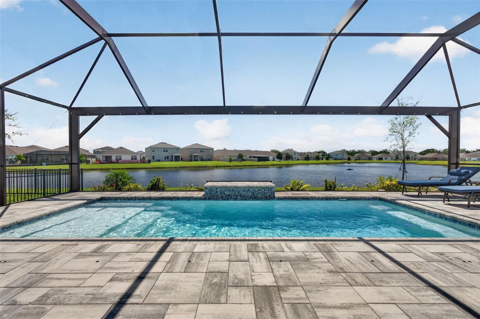 Ideal lake front setting with lake fountainPool has a sundeck, waterfall, bench setting on 2 sides and spa jets and converts to a hot tub - 17206 RESERVA DR, BRADENTON