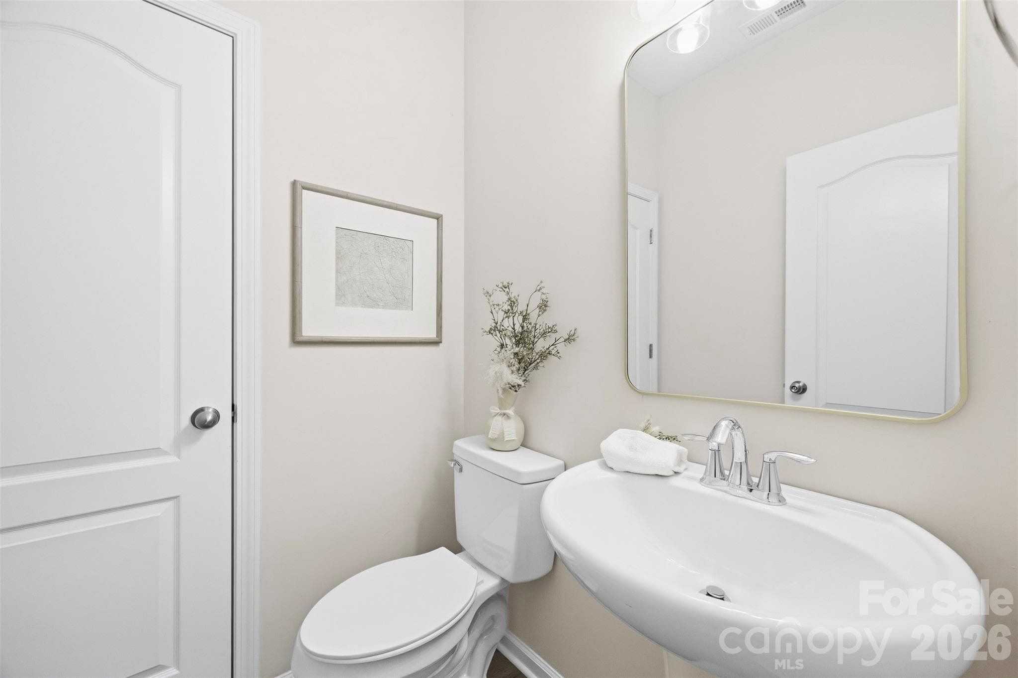 Updated main-level half bath features a new mirror and updated fixtures - 2015 Kensley Drive, Waxhaw