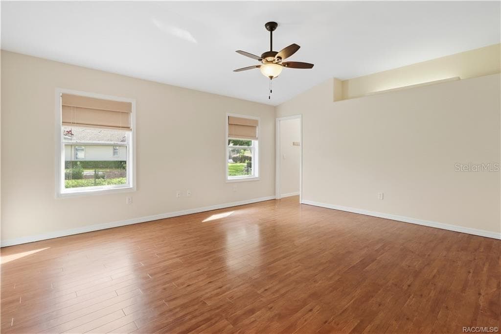 PRIMARY BEDROOM – Spacious primary bedroom featuring LUXURY VINYL PLANK FLOORING, ceiling fan, lighted plant shelf, neutral walls & two windows providing natural light. - 6410 W CANNONDALE DR, CRYSTAL RIVER