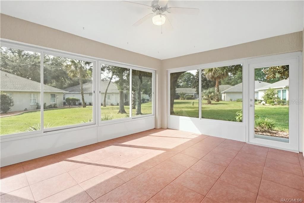 ENCLOSED SUNROOM – Expansive enclosed sunroom surrounded by large windows overlooking the landscaped backyard, with tile flooring, ceiling fan & exterior door. - 6410 W CANNONDALE DR, CRYSTAL RIVER