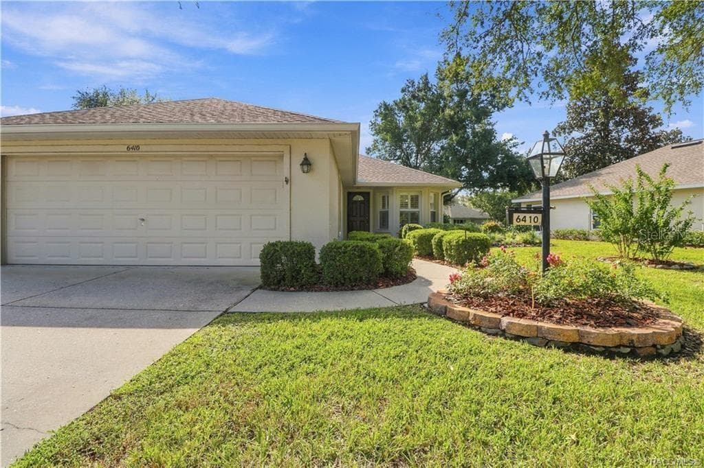 FRONT EXTERIOR – Inviting curb appeal with a manicured lawn, established landscaping, colorful planting beds, covered entry & attached 2-car garage. The front bay-style windows add architectural interest while bringing natural light inside. - 6410 W CANNONDALE DR, CRYSTAL RIVER