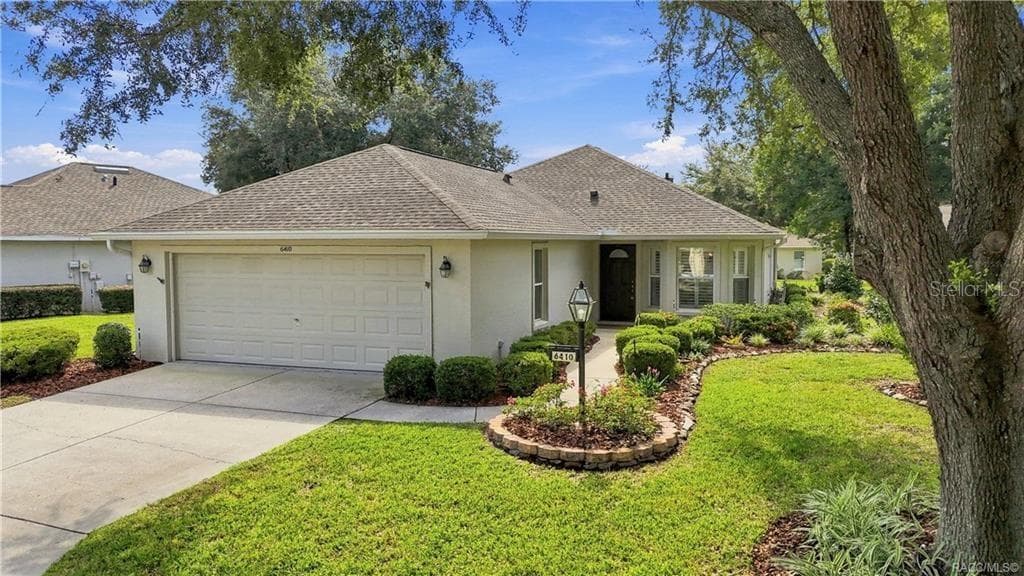 FRONT EXTERIOR – Attractive front elevation framed by mature shade trees, manicured landscaping & a curved walkway leading to the covered entry, plus an attached 2-car garage. - 6410 W CANNONDALE DR, CRYSTAL RIVER