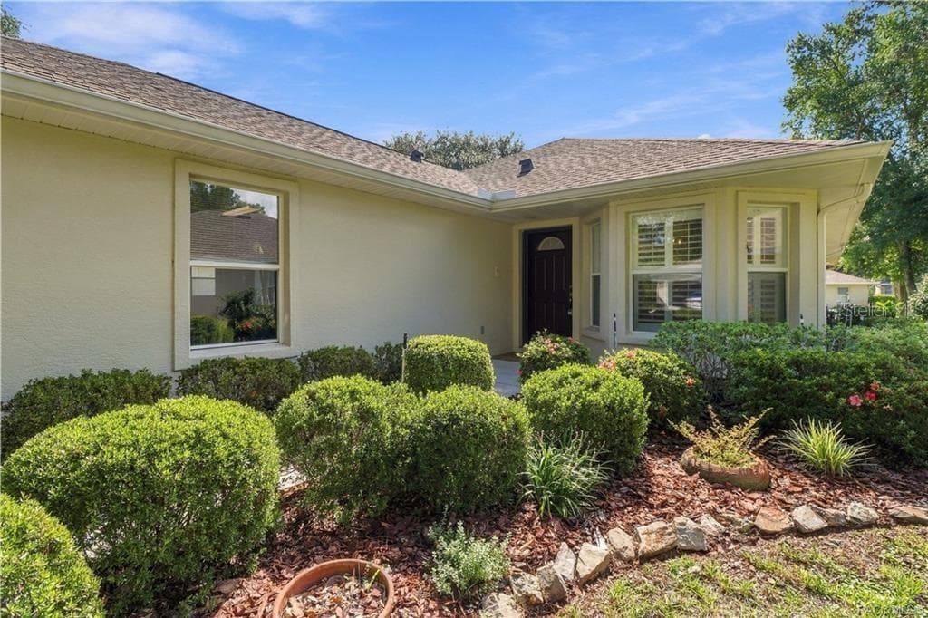 COVERED ENTRY – A closer look at the sheltered front entrance surrounded by mature landscaping. The grouping of front windows with plantation shutters gives the home a polished appearance from both inside & out. - 6410 W CANNONDALE DR, CRYSTAL RIVER