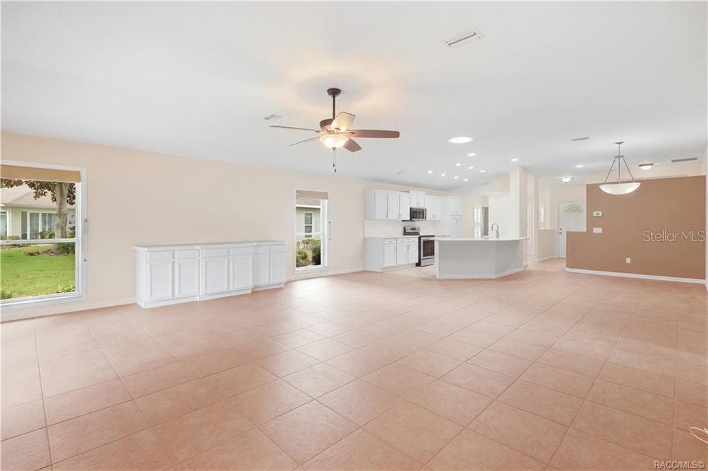 OPEN-CONCEPT LIVING – Wide-angle view showing just how open the living area feels, with the kitchen, dining space & great room visually connected. Built-in cabinetry provides additional storage while large windows add natural light. - 6410 W CANNONDALE DR, CRYSTAL RIVER