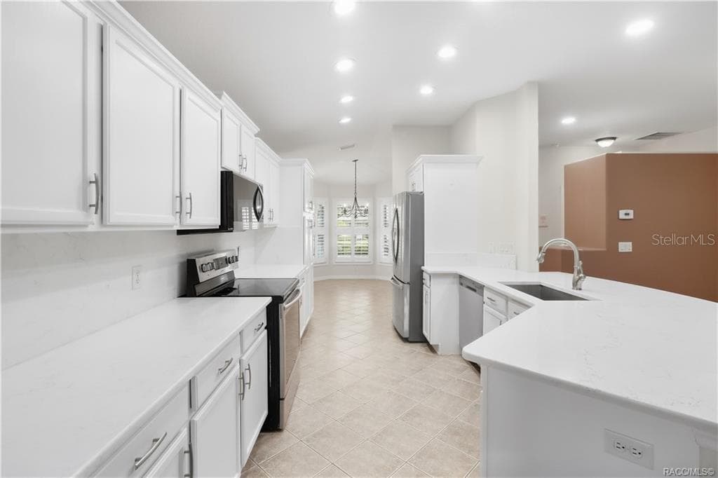 REMODELED KITCHEN – Bright, updated kitchen with crisp white cabinetry, quartz countertops, stainless-steel appliances, recessed lighting & a large peninsula that provides additional prep space while keeping the kitchen connected to the living area. - 6410 W CANNONDALE DR, CRYSTAL RIVER