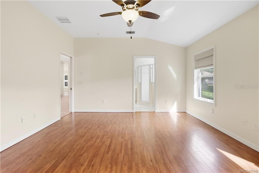 PRIMARY BEDROOM – Alternate view of the primary suite highlighting the LUXURY VINYL PLANK FLOORING & direct access to the adjoining primary bathroom. LIGHT & BRIGHT - 6410 W CANNONDALE DR, CRYSTAL RIVER