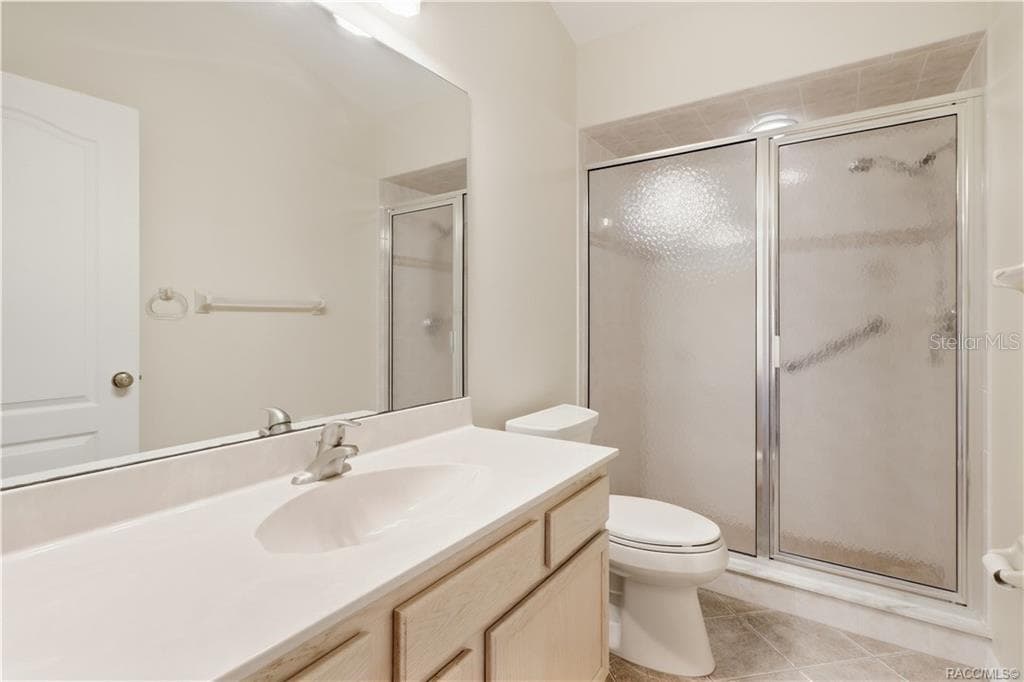 GUEST BATHROOM – Full guest bath with vanity, large wall mirror, tile flooring & shower with textured glass enclosure. - 6410 W CANNONDALE DR, CRYSTAL RIVER
