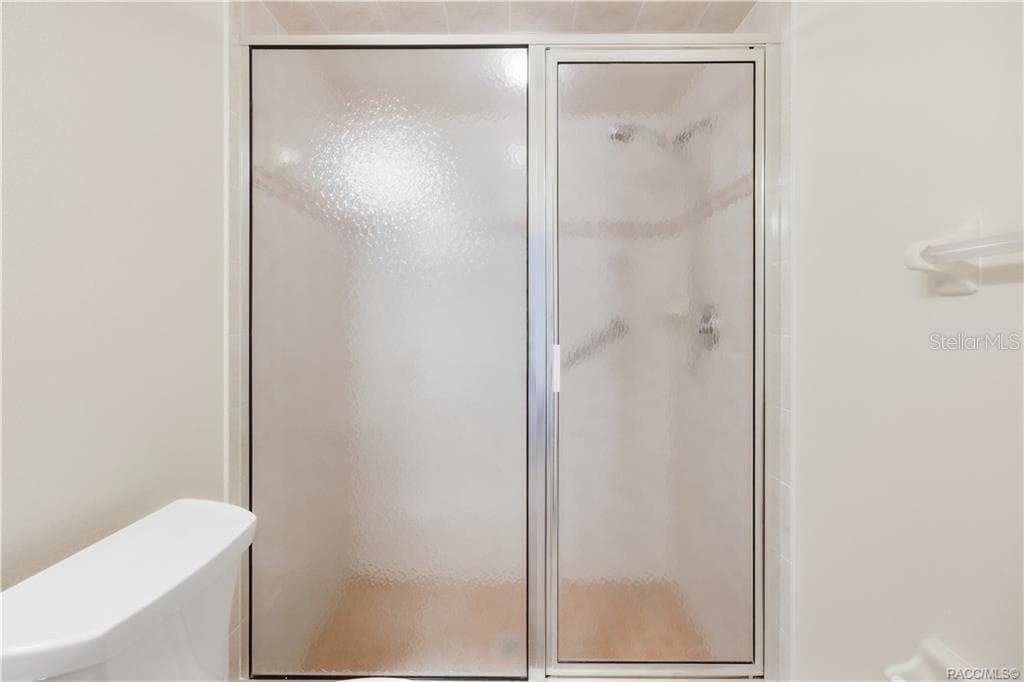 GUEST BATHROOM – SHOWER – Closer view of the shower with textured sliding-glass enclosure & tiled surround. - 6410 W CANNONDALE DR, CRYSTAL RIVER