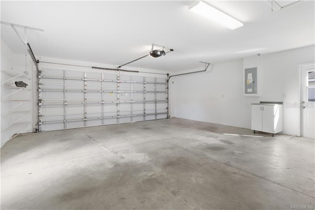 2-CAR GARAGE – Spacious attached garage with automatic garage-door opener, overhead lighting, concrete flooring, wall shelving & additional storage cabinet. - 6410 W CANNONDALE DR, CRYSTAL RIVER