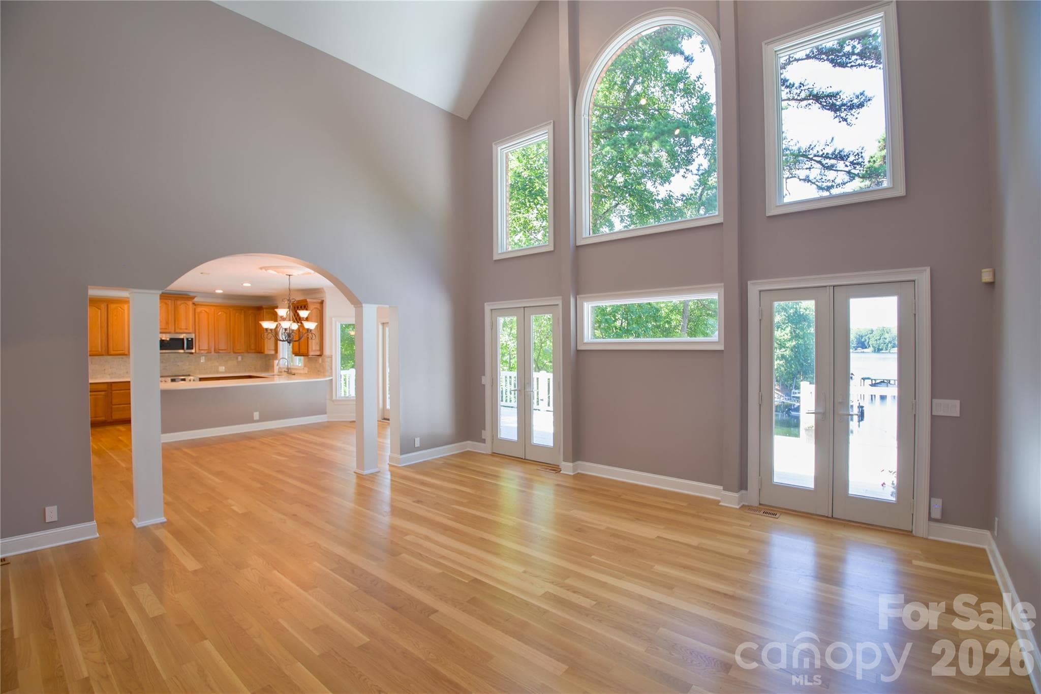 Bright and airy great room with newly refinished hardwood floors flows into dining area and kitchen through stunning arch. - 140 Holt Lane, Mooresville