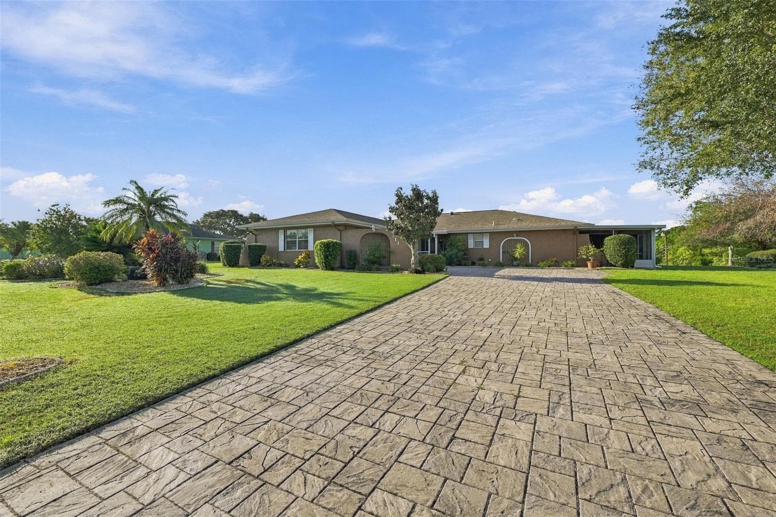 Beautiful manicured landscaping and custom pavered driveway, which is long and wide for multiple vehicles. - 211 STONEHAM DR, SUN CITY CENTER