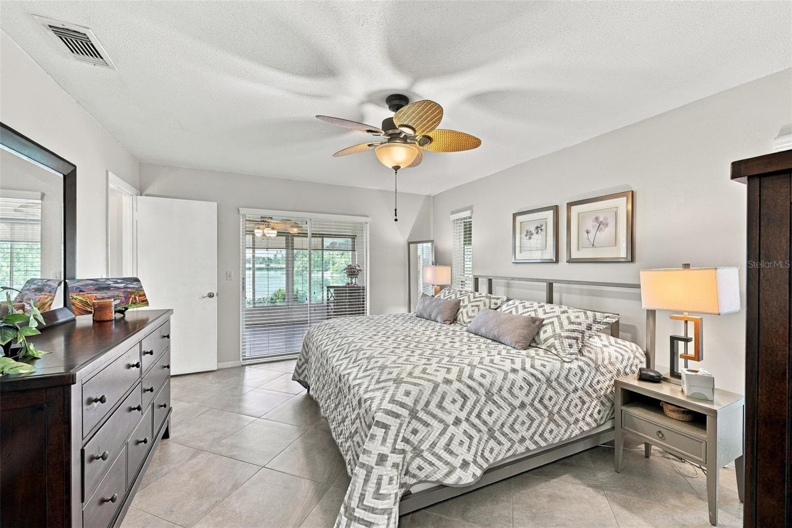 Primary bedroom is large, bright and relacing. Notice the consistent flooring throughout the home. Large beautiful sliding glass doors allow natural Florida sunshine to filter into the room with a view of the water. - 211 STONEHAM DR, SUN CITY CENTER
