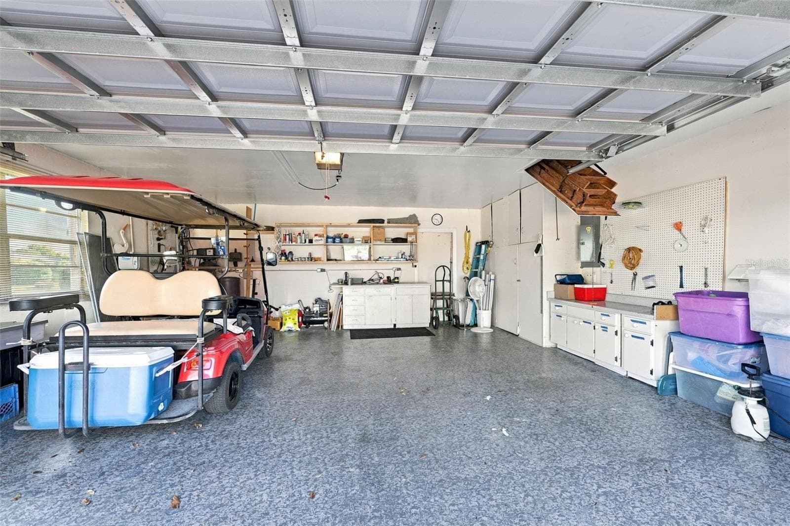 The garage is oversized, with epoxy flooring, storage cabinets and YES, the golf cart is included. Notice the attic stairs offer full storage capability, if desired. - 211 STONEHAM DR, SUN CITY CENTER