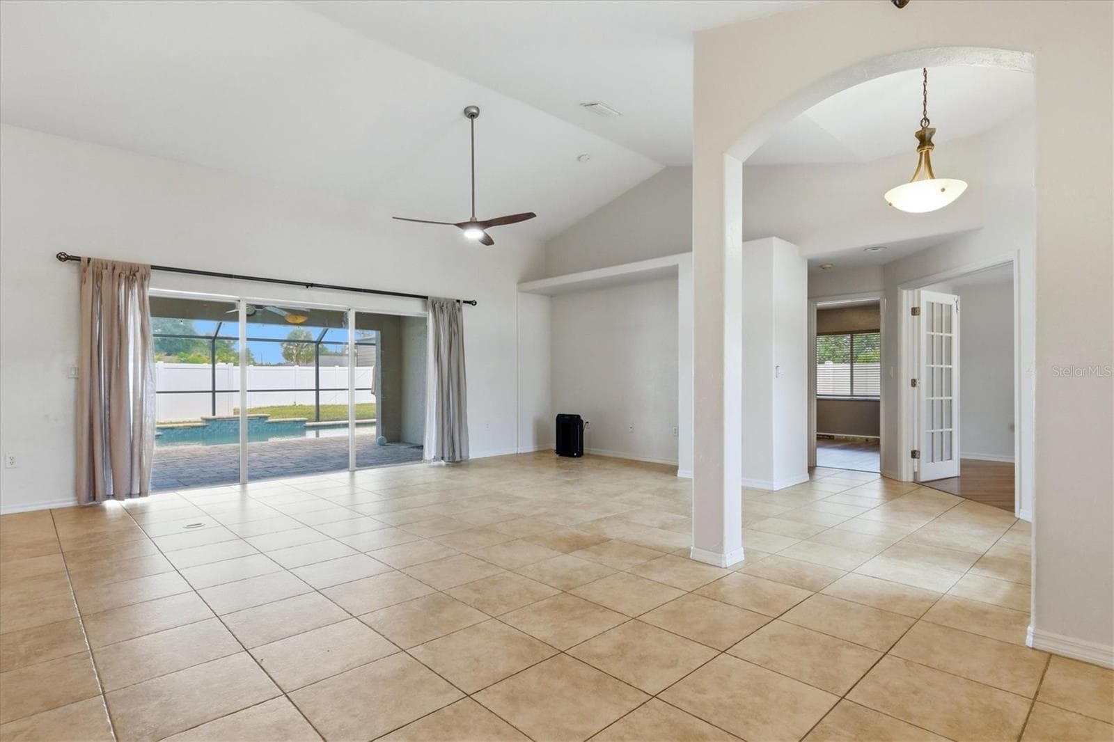 this angle of living room shows full sliders, far right is 4th bedroom with french doors then down the hall to the other two guest rooms and bath 2 - 23108 AUGUST AVE, PORT CHARLOTTE