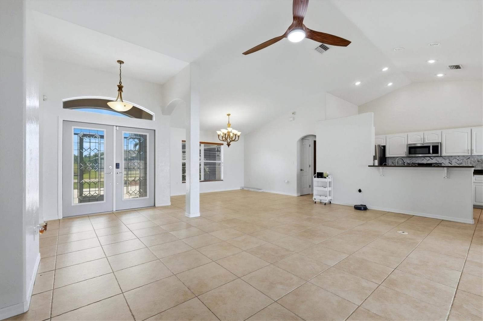from living room sliders looking towards front of home, entry, dining, kitchen and through arched opening is laundry room to left that leads out to garage - 23108 AUGUST AVE, PORT CHARLOTTE