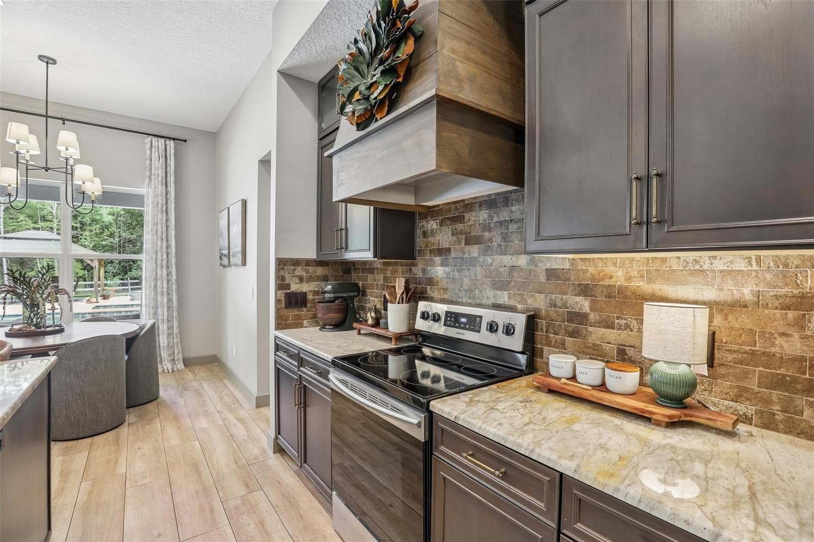 The Kitchen is truly a CHEF'S DREAM, featuring an abundance of cabinetry and counter space, STAINLESS STEEL APPLIANCES, a striking BRICK BACKSPLASH, stylish range hood, generous island with BREAKFAST BAR SEATING and a convenient pantry closet. - 19179 SABAL ST, ORLANDO